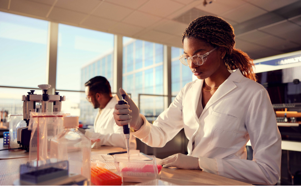 Female scientist, side view, holding single pipette, male scientist working in the background